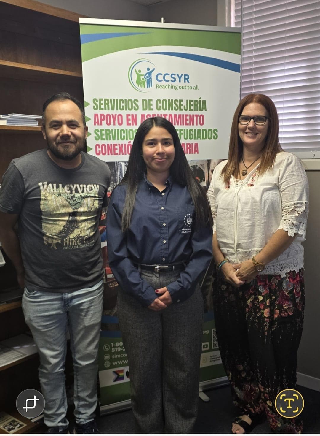 Three staff members in front of an organisational banner