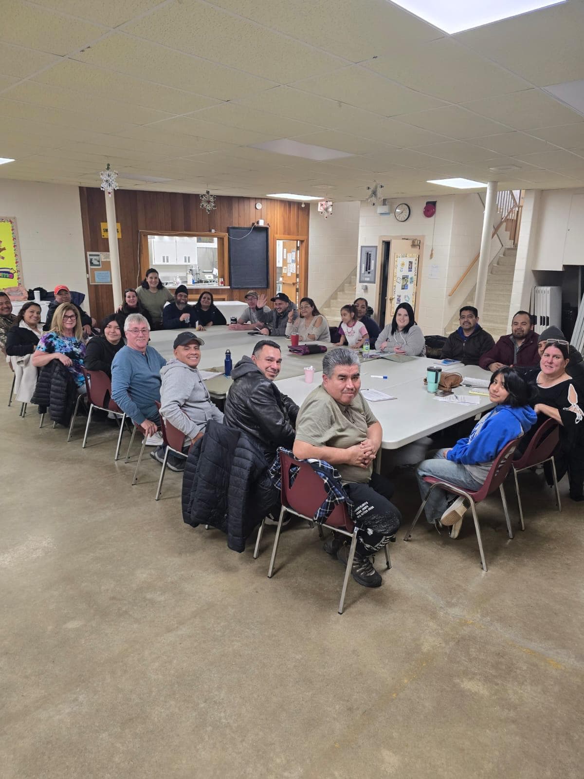 Families and community members gathered around a large table for a meeting