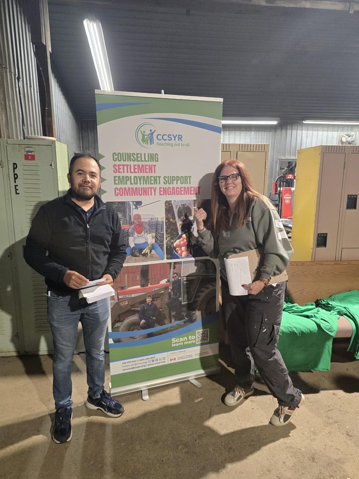 Two outreach workers with an information banner at a farm visit