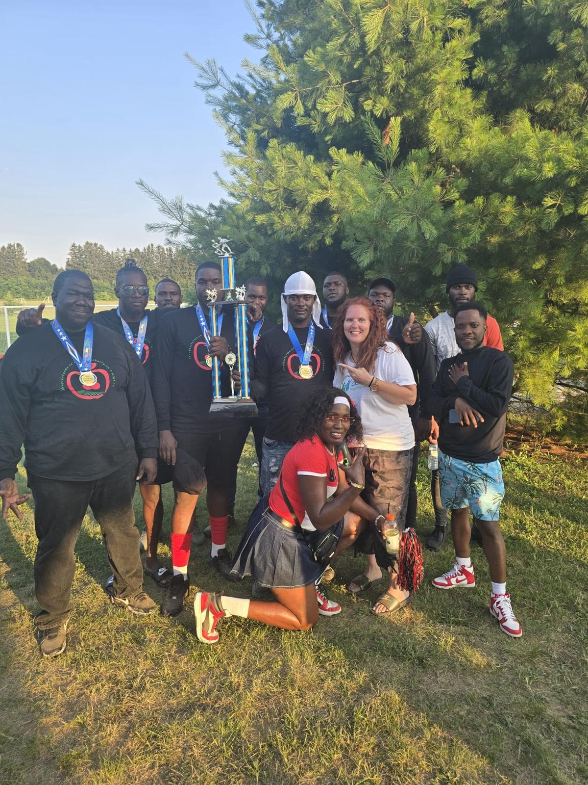 Winning soccer team posing with medals and a large trophy
