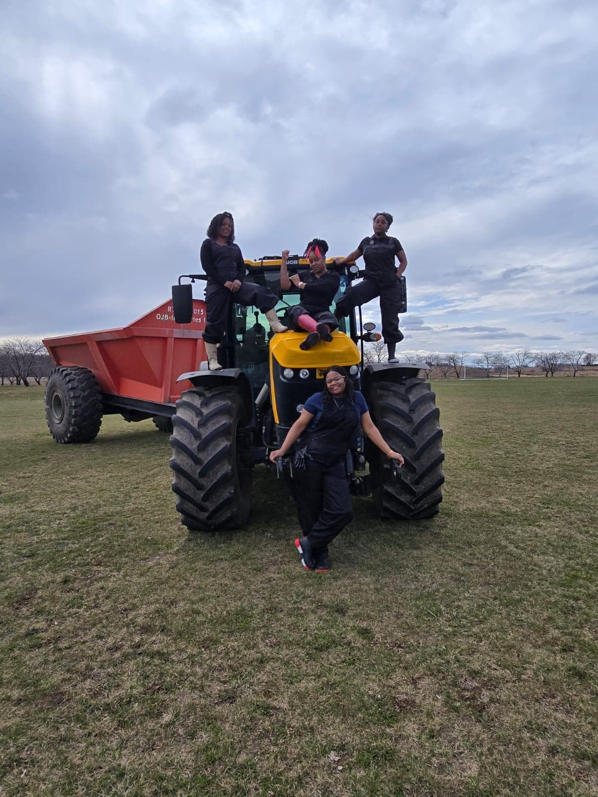 Women posing on a large JCB tractor during a farm visit